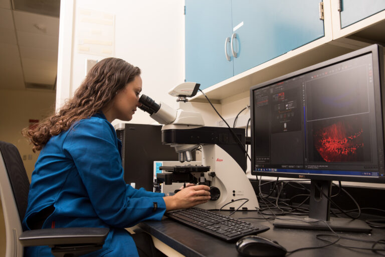 Christie D. Fowler Looking into Microscope